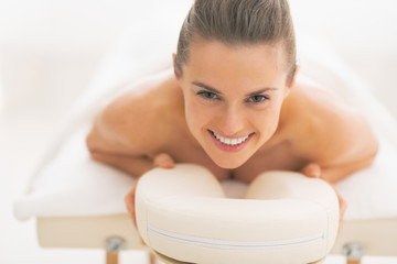 Happy young woman laying on massage table