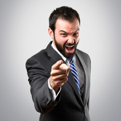 Young businessman screaming over grey background