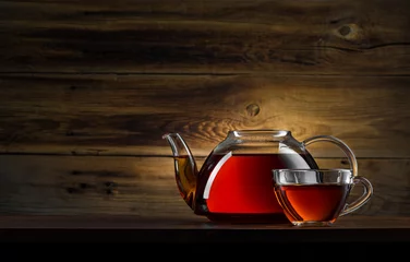 Papier Peint photo Theé glass teapot with black tea on wooden background