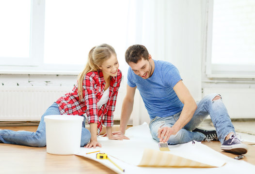 smiling couple smearing wallpaper with glue