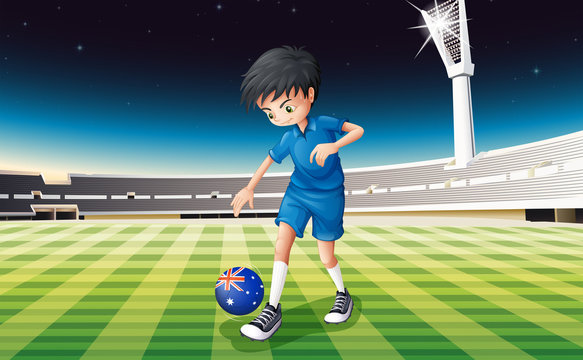 A boy at the field using the ball with the flag of Australia