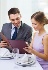 smiling couple with menu at restaurant