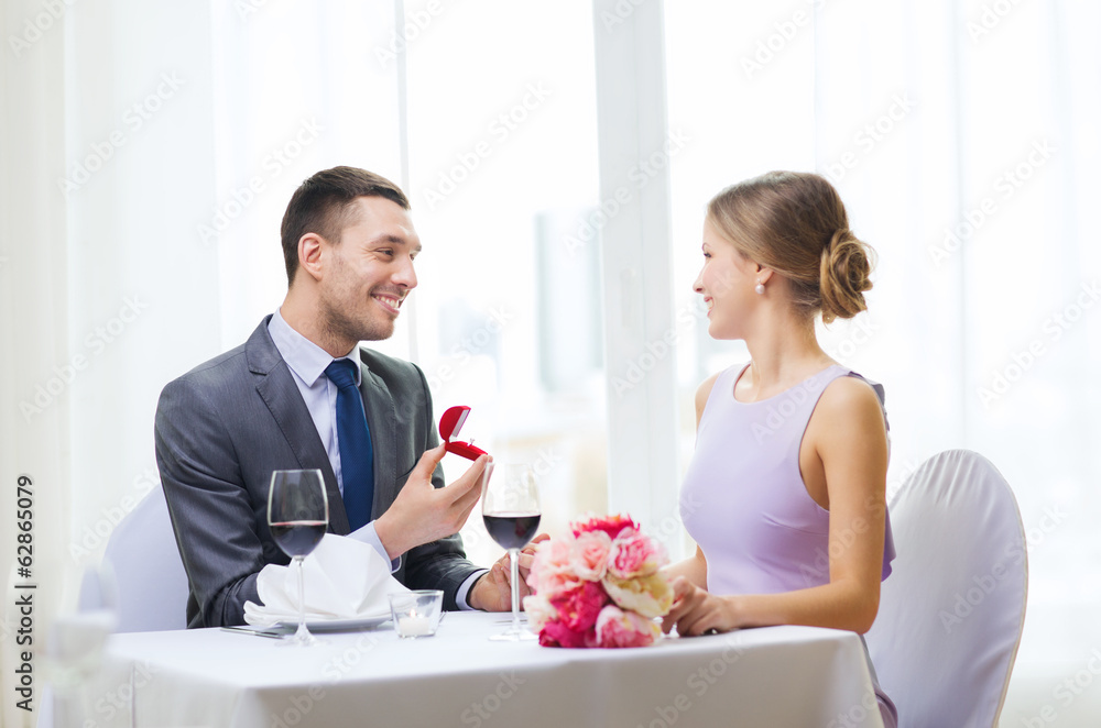 Poster man proposing to his girlfriend at restaurant