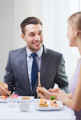 smiling couple eating sushi at restaurant