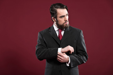 Retro 1900 fashion man with beard wearing grey suit and red tie.