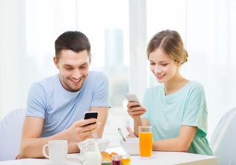 Obraz na płótnie Canvas smiling couple with smartphones reading news