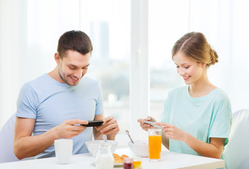 smiling couple with smartphones taking picture