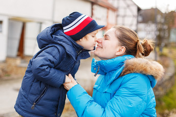 Adorable caucasian little boy and mother hugging on bridge, outd