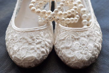 White bridal shoes with pearl bracelet