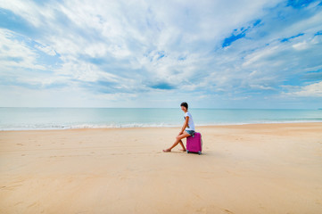 Fototapeta na wymiar Woman with a suitcase on the beach