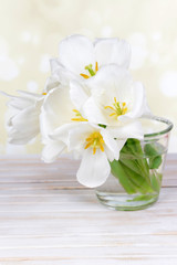 Naklejka na ściany i meble Beautiful bouquet of white tulips on table on light background