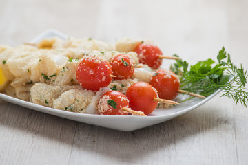 Spiedini di pesce crudi nel piatto ceramica bianco