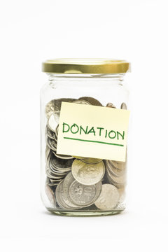 Isolated coins in jar with donation label