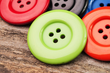 Red, green and other plastic buttons on wood