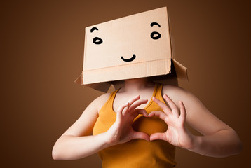 Young woman gesturing with a cardboard box on her head with smil