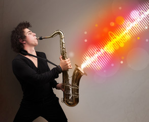 Young man playing on saxophone with colorful sound waves