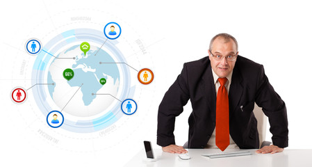 businessman standing at desk with globe and social icons