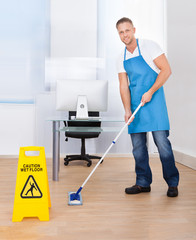 Warning notice as a janitor mops the floor