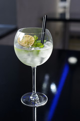 Fresh cocktail with ice, mint and lime on the dark background