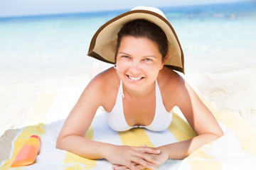 Woman in bikini top lying on beach towel at seashore