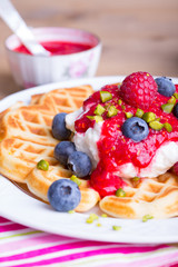 Frische Waffel mit Sahne, Beeren und Pistazien