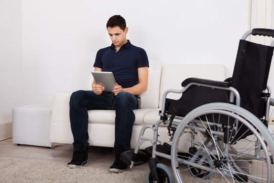 Handicapped Man Using Digital Tablet On Sofa