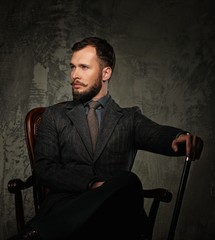 Handsome well-dressed with stick sitting in leather chair