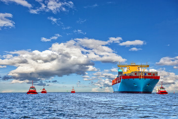 Tugboat assisting container cargo ship to harbor.