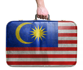 Tourist hand holding vintage leather travel bag with flag of Mal