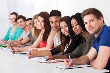 College Students Sitting In A Row At Desk