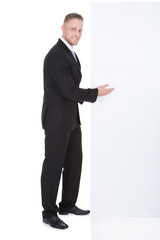 Stylish businessman pointing to a blank white sign
