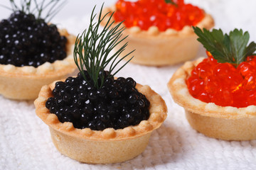 four tartlets with red and black fish caviar horizontal. closeup