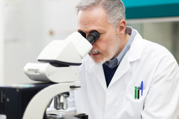Scientist conducting research looking through microscope