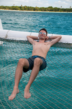 Man relaxingo on a catamaran sailing boat near Saona, Caribbean
