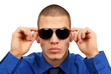 Young man closeup at blue shirt and tie holds sunglasses