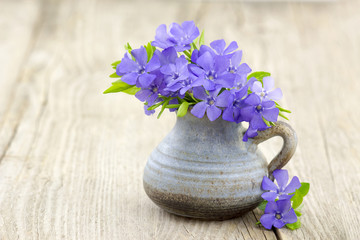 Beautiful spring flowers in a vase on wooden background