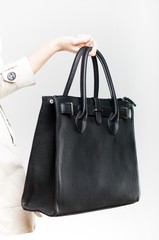 Elegant woman holding on finger black bag, closeup