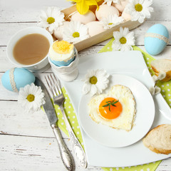 Easter table setting with flowers and eggs on old wooden table