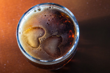 Close-up heart shaped ice cubes in glass of cola soda drink