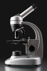 close up of a silver microscope, with black background