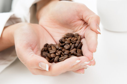 Womans Hands full of roasted coffe beans shaped as heart