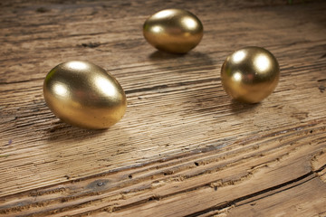 golden easter eggs in nest on vintage rustic wooden background