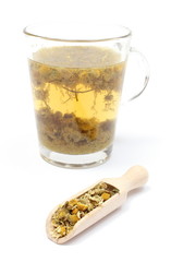Dried chamomile on wooden spoon and cup of beverage