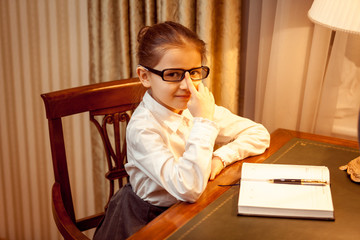 girl in eyeglasses sitting behind table with notebook