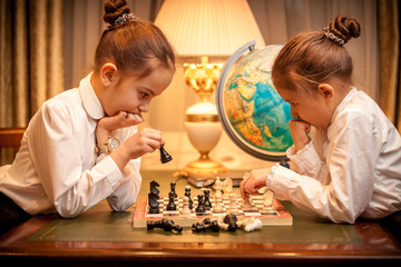 Two sisters in school uniform playing chess
