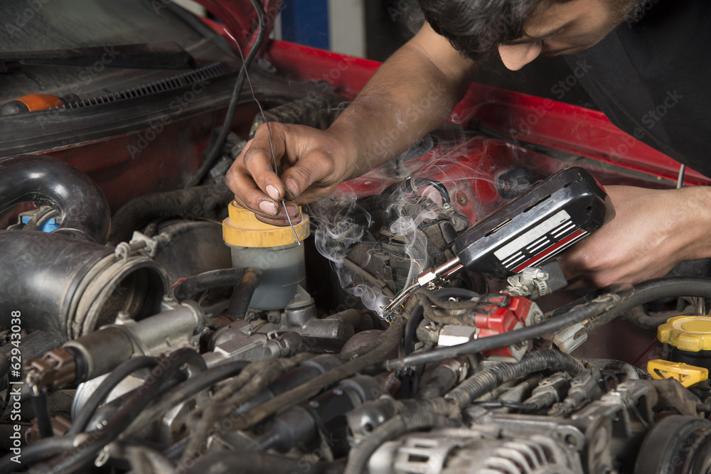 Wall mural Car mechanic melting solder wire on soldering iron tip