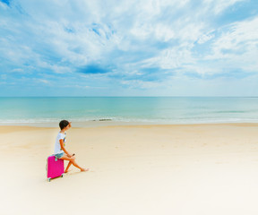 Woman with a suitcase on the beach