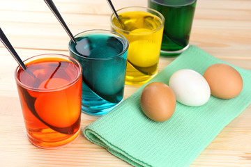 Glasses with paint for Easter eggs and eggs, close up
