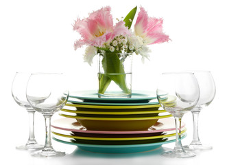 Stack of colorful ceramic dishes and flowers, isolated on white