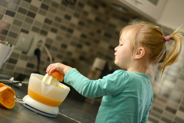 Bébé fille faire du jus d'orange dans la cuisine